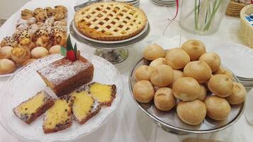 A table with various baked goods including a pie, pastries, and bread rolls.