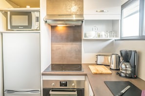 Uma cozinha compacta equipada com micro-ondas, fogão, forno e máquina de café.