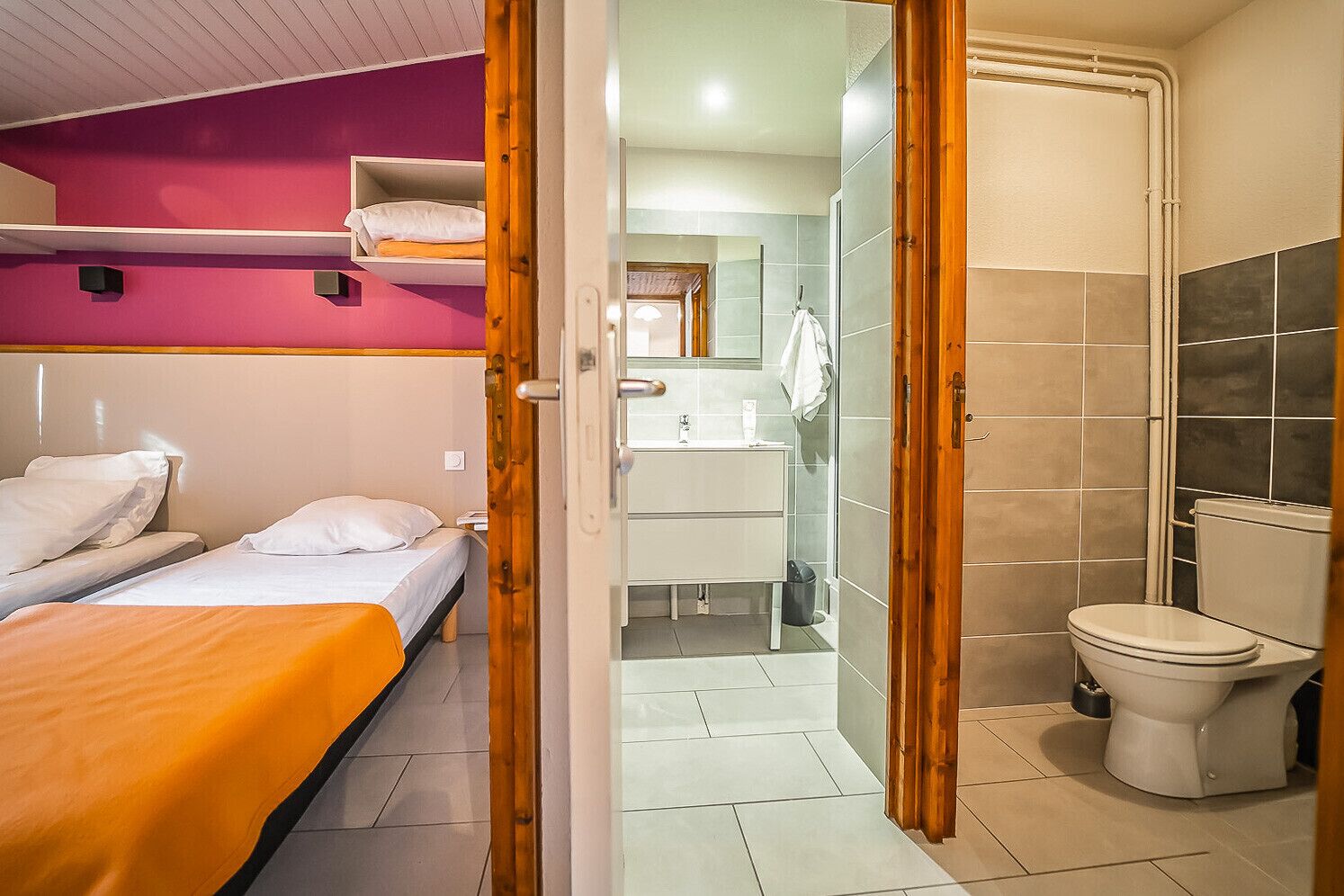 A room with a bunk bed, a bathroom with a toilet and sink, and a shower area.