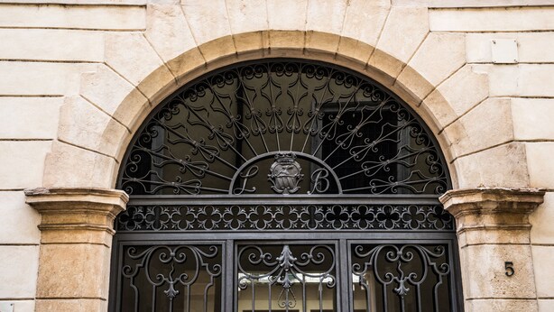 An arched metal gate with intricate designs and a coat of arms, set within a stone building facade. - Apartment Verona Historical Center 50 meters from the Arena and Piazza Brà - Opera (Verona)