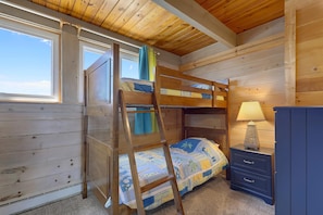 Quarto com beliche, escrivaninha com abajur e janela.