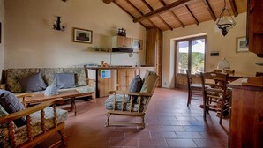 Ein gemütliches Wohnzimmer mit Holzboden, einer Couch, einem Esstisch und Stühlen.