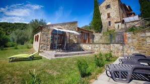 Ein Steinhaus mit Terrasse, Sitzgelegenheiten im Freien und Blick auf die umliegende Landschaft.