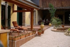 A courtyard with outdoor seating, potted plants, and a stone pathway.