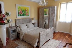 Une chambre à coucher avec un lit en bois, une armoire, une table de chevet et un tableau accroché au mur.