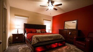 A bedroom with a bed, nightstands, a dresser, a mirror, and a ceiling fan.