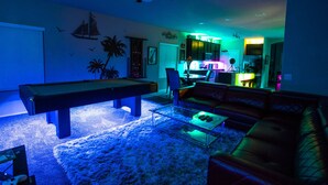 A living room with a pool table, a leather couch, and a coffee table.