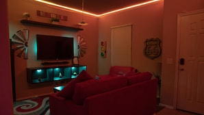 A living room with a red sofa, a flat-screen TV, and a Route 66 sign on the wall.