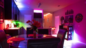 A modern kitchen with a glass dining table, chairs, and a refrigerator.