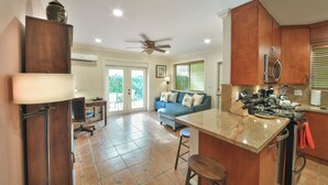 A modern kitchen with a central island, a dining area with a blue sofa, and a ceiling fan. - Walk to GAY Wilton Drive, Pool, Queen Bed, Kitchen, Living Room, Patio, WiFi, #3 (Wilton Manors)
