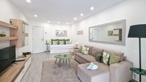 A modern living room with a sofa, TV, and a coffee table. - Tropical Apartment with Terrace Praia da Rocha (Portimão)
