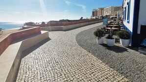 A cobblestone promenade with outdoor seating, overlooking a coastal area with buildings and a clear sky. - Tropical Apartment with Terrace Praia da Rocha (Portimão)