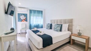 A modern hotel room with a bed, bedside table, TV, and a small desk. - Tropical Apartment with Terrace Praia da Rocha (Portimão)