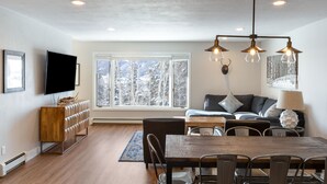 Una sala de estar moderna con comedor, ventanas amplias y un televisor de pantalla plana.
