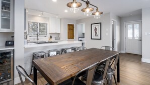 Una cocina moderna con armarios blancos, una mesa de comedor de madera y un horno empotrado.
