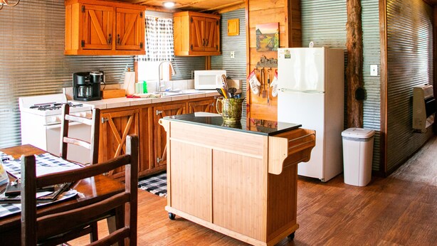 A kitchen with wooden cabinets, a microwave, a refrigerator, and a coffee maker. - Victory Suite - Rustic Cabin (Hot Springs)