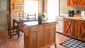 A kitchen with wooden cabinets, a central island, and a stove. - Victory Suite - Rustic Cabin (Hot Springs)