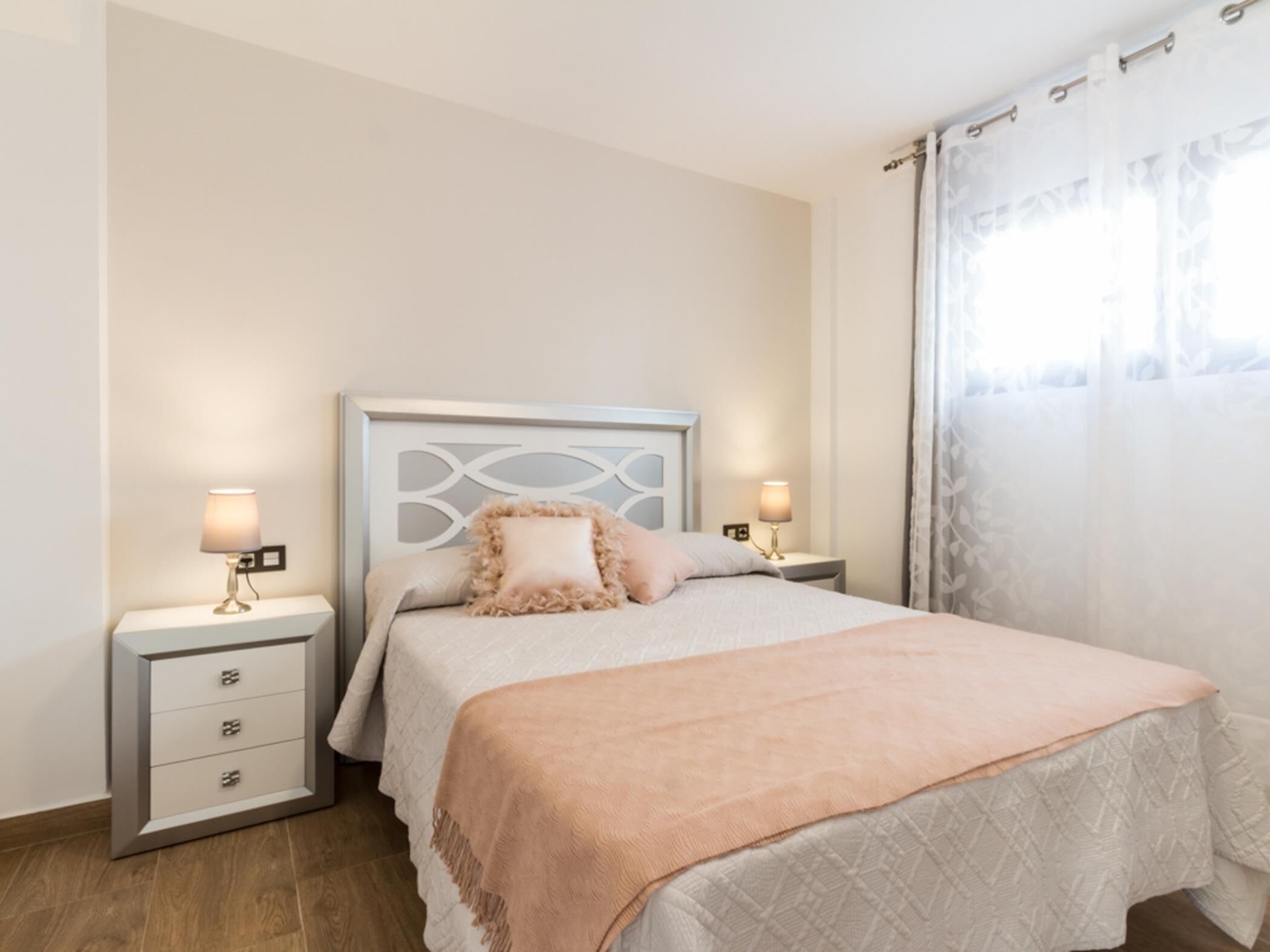 A neatly arranged bedroom with a bed, two bedside tables, and a nightstand.