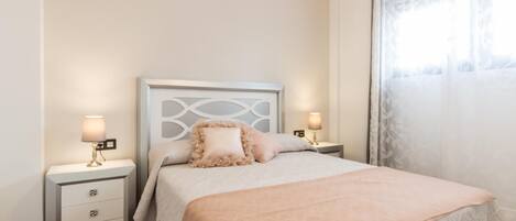 A neatly arranged bedroom with a bed, two bedside tables, and a nightstand.
