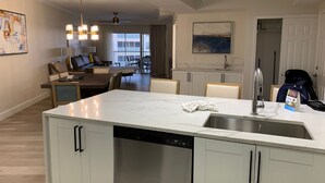 Una cocina moderna con una isla grande, lavavajillas integrado y un comedor con sofá y sillas.