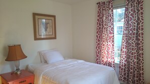 A bedroom with a bed, a nightstand, a lamp, a framed picture on the wall, and patterned curtains. - Charleston "Home-Away-from-Home" - Close to All Major Attractions! (North Charleston)