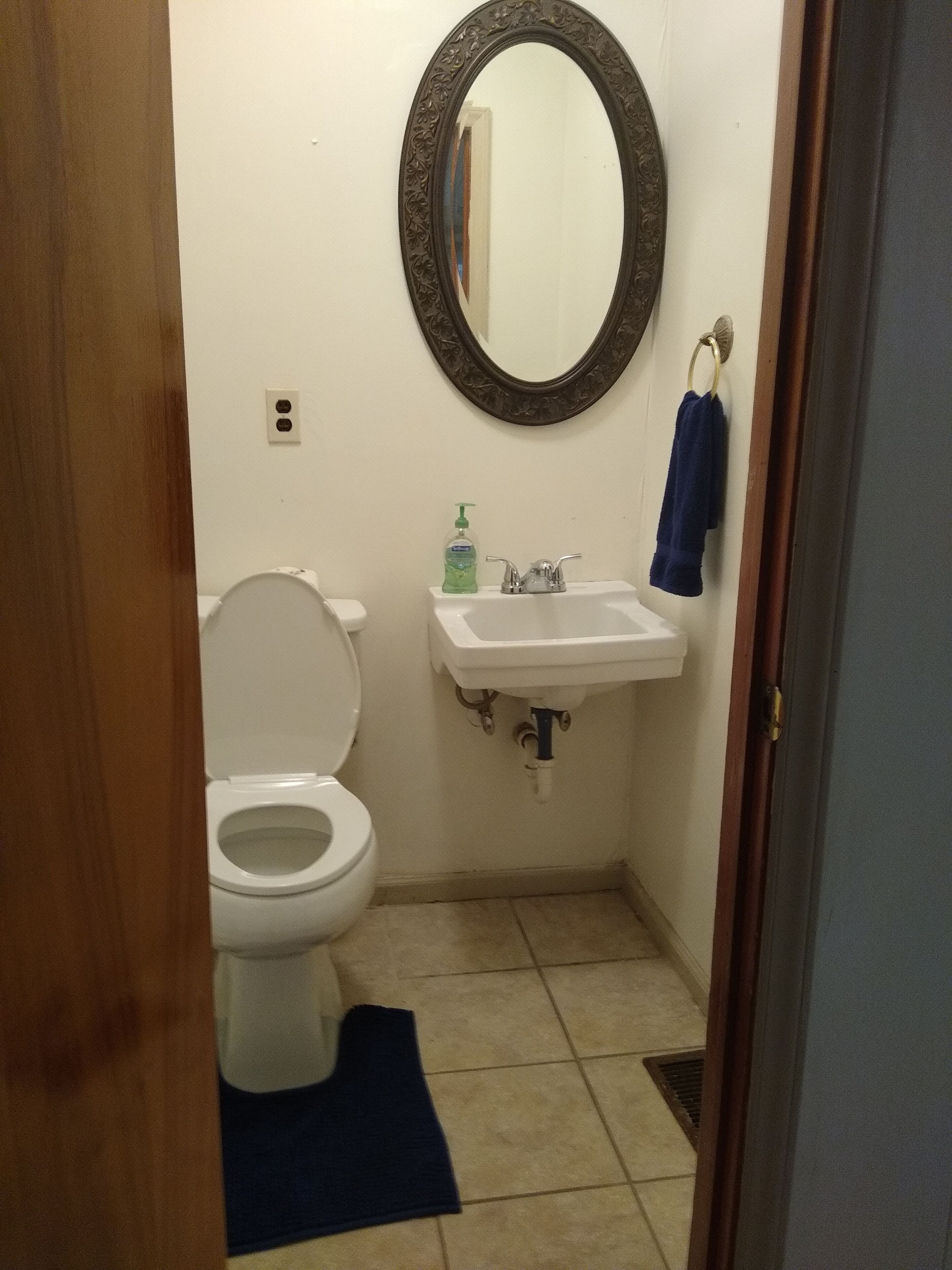 A small bathroom with a toilet, sink, and mirror.