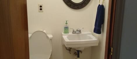 A small bathroom with a toilet, sink, and mirror.