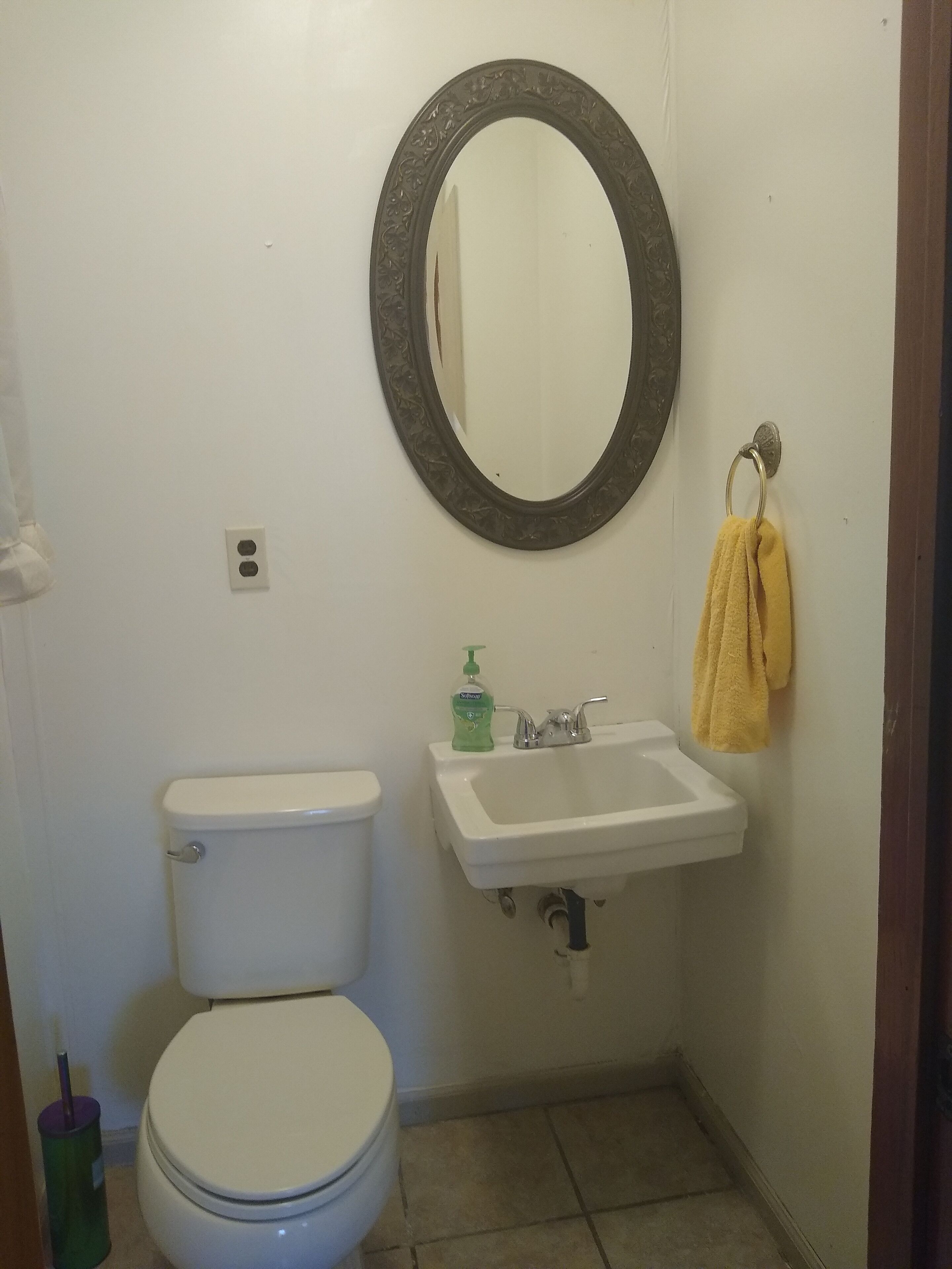 Et lille badeværelse med toilet, vask og spejl.