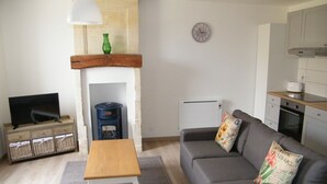 Una sala de estar con sofá, televisión, chimenea y zona de cocina.