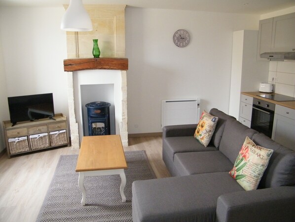 Ein Wohnzimmer mit Sofa, Fernseher, Kamin und Küchenzeile.