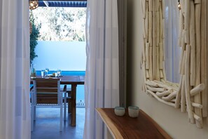 A room with a wooden table and chairs, a view of the sea, and a wall decorated with wooden elements. - Traditional Villa with Private Heated Pool (Santorini)