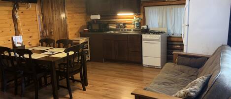 A cozy cabin interior with a dining area, kitchen, and living space.