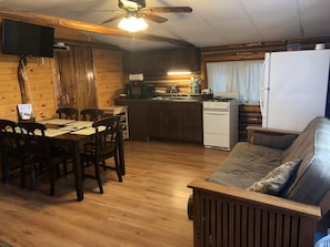 Un interior acogedor de cabaña con comedor, cocina y sala de estar.