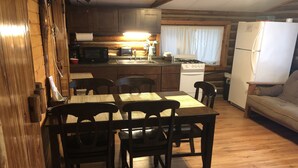 A compact kitchen with wooden cabinets, a microwave, a stove, and a refrigerator. - Cabin 6 Lake Cabins Resort on Fife Lake (Fife Lake)