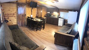 A cozy cabin interior with a dining area, kitchen, and seating space. - Cabin 6 Lake Cabins Resort on Fife Lake (Fife Lake)