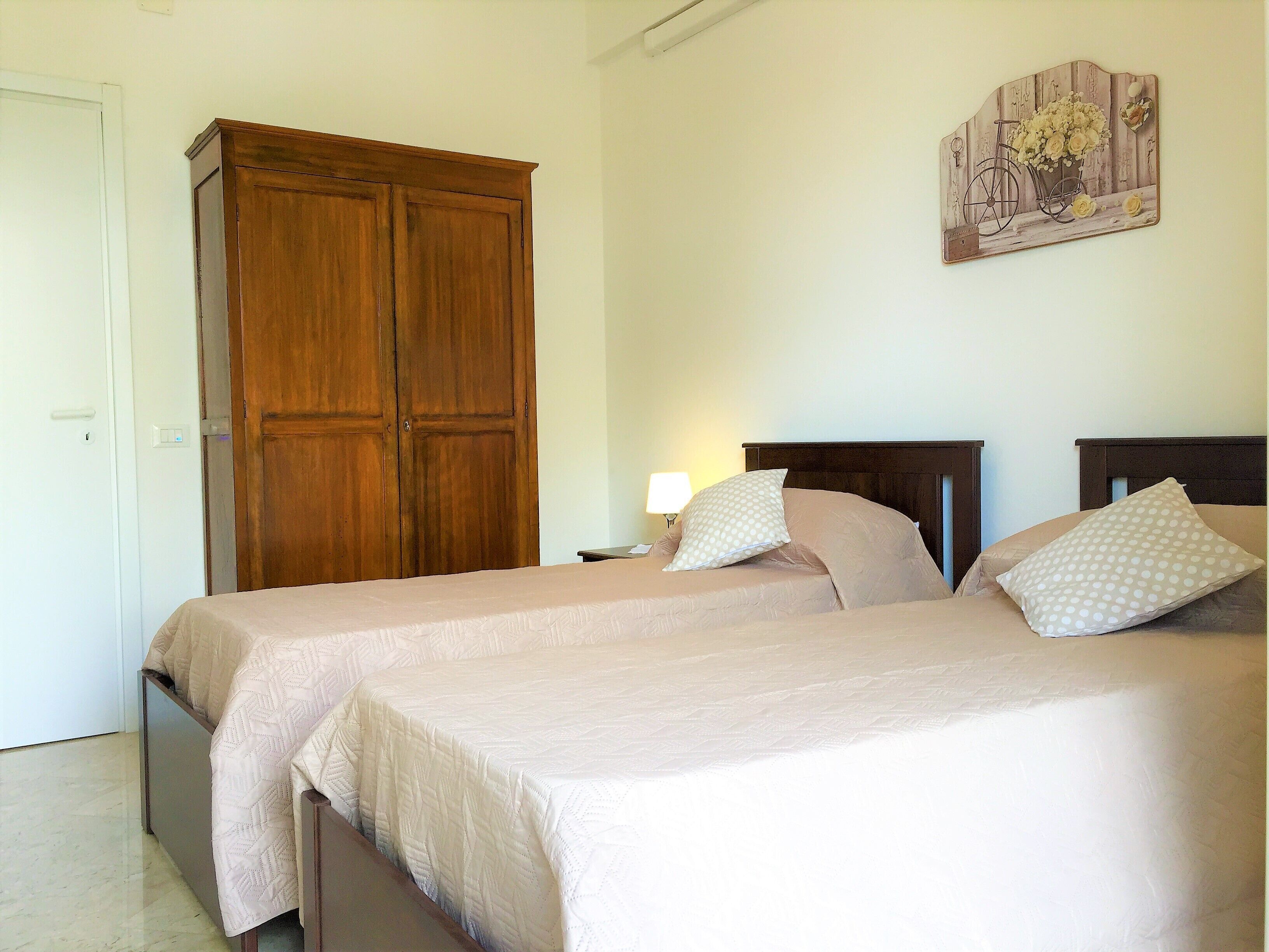 Une chambre avec deux lits, une armoire et un élément décoratif fixé au mur.