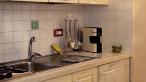 A kitchen with white cabinets, a stainless steel sink, and a coffee maker.