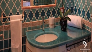 A bathroom with a sink, mirror, and decorative tiles.