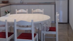 A modern kitchen with white cabinets, a round dining table with white chairs, and a built-in oven. - Apartment in Murter with Terrace, Air condition, WIFI, Washing machine (125-4) (Murter)