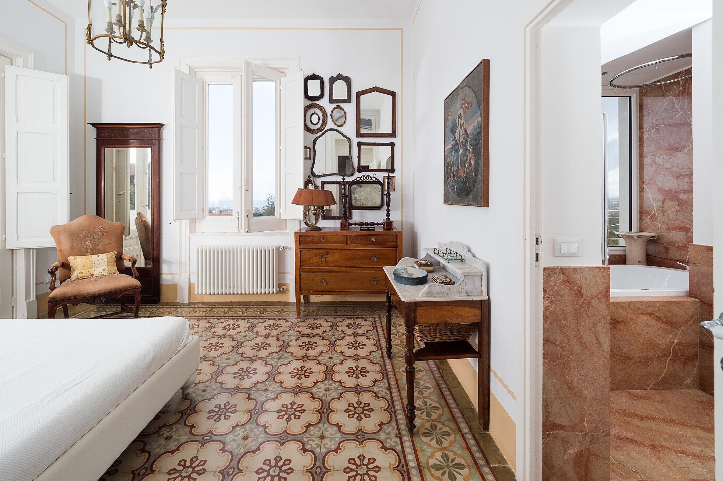 A bedroom with a bed, a chair, a dresser, a mirror, and a radiator.