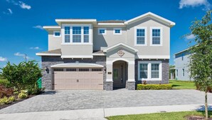 A two-story house with a garage, a front entrance with a decorative arch, and a well-maintained lawn. - Spacious Abode with Spillover Spa in Encore (Kissimmee)