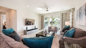 A modern living room with a sofa set, a coffee table, and a TV on a white wall. - Spacious Abode with Spillover Spa in Encore (Kissimmee)