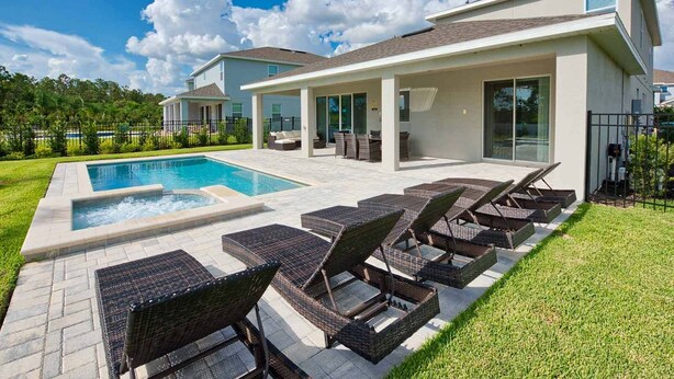 A modern house with a swimming pool, outdoor seating, and a well-maintained lawn. - Spacious Abode with Spillover Spa in Encore (Kissimmee)