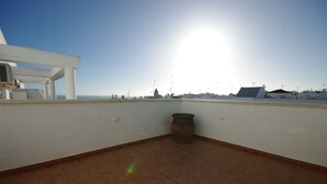 A rooftop terrace with a view of the sea, a large terracotta pot, and a white structure. - 192 - Ático El Cielo (Conil de la Frontera)