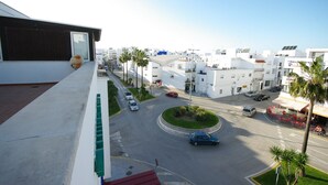 A residential area with white buildings, a roundabout, and palm trees. - 192 - Ático El Cielo (Conil de la Frontera)