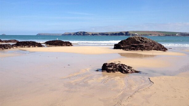 A beach with large rocks, clear blue sky, and calm sea. - Roswidden on the cliff (Treyarnon Bay)