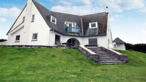 A large, white, two-story house with a steeply pitched roof, a small porch, and a staircase leading to the entrance. - Roswidden on the cliff (Treyarnon Bay)