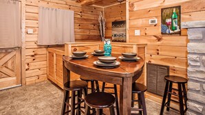A wooden interior with a dining table set for four, a bar stool, and a decorative vase. - 🌄 A Great Escape 🍃 Mountain Views, Resort Pool, Hot Tub & Game Room (Sevierville)