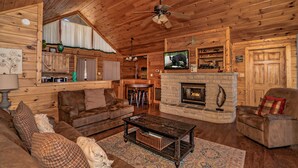 A cozy cabin interior with a fireplace, wooden furniture, and a television. - 🌄 A Great Escape 🍃 Mountain Views, Resort Pool, Hot Tub & Game Room (Sevierville)