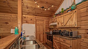 A wooden cabin-style kitchen with granite countertops, stainless steel sink, and built-in appliances including a stove, microwave, and oven. - 🌄 A Great Escape 🍃 Mountain Views, Resort Pool, Hot Tub & Game Room (Sevierville)
